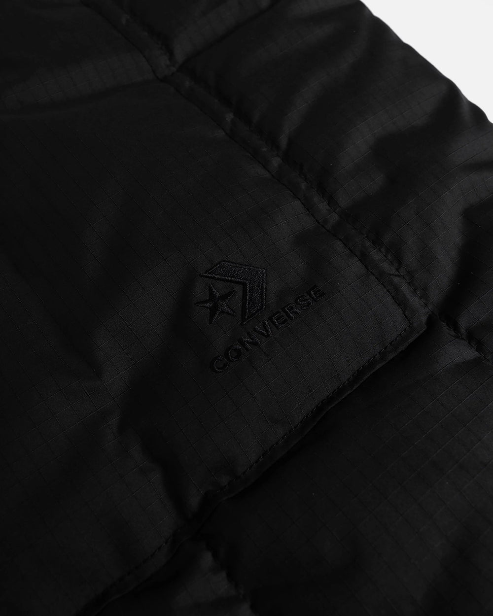 Detail of embroidered Converse Star Chevron logo on the black quilted side of Patta reversible vest.